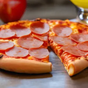 A pepperoni pizza, an apple, a mandarin and a glass of lemonade, Closeup