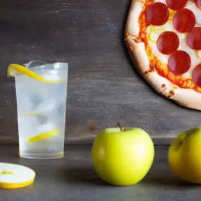 A pepperoni pizza, an apple, a mandarin and a glass of lemonade with lemons, Closeup